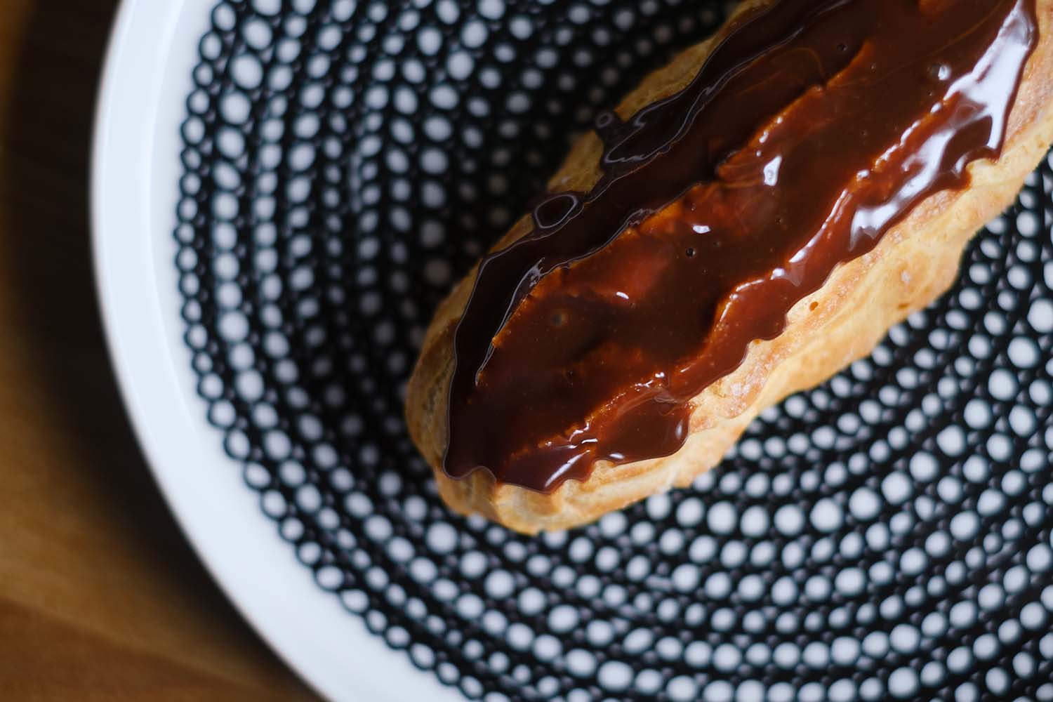 eclair tuulihattuleivos suklaakuorrutteella Marimekon lautasella. Valokuva.